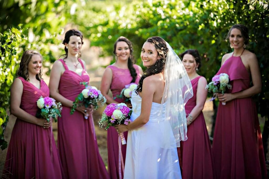 A bride and her bridesmaids in fuschia dresses all holding flowers